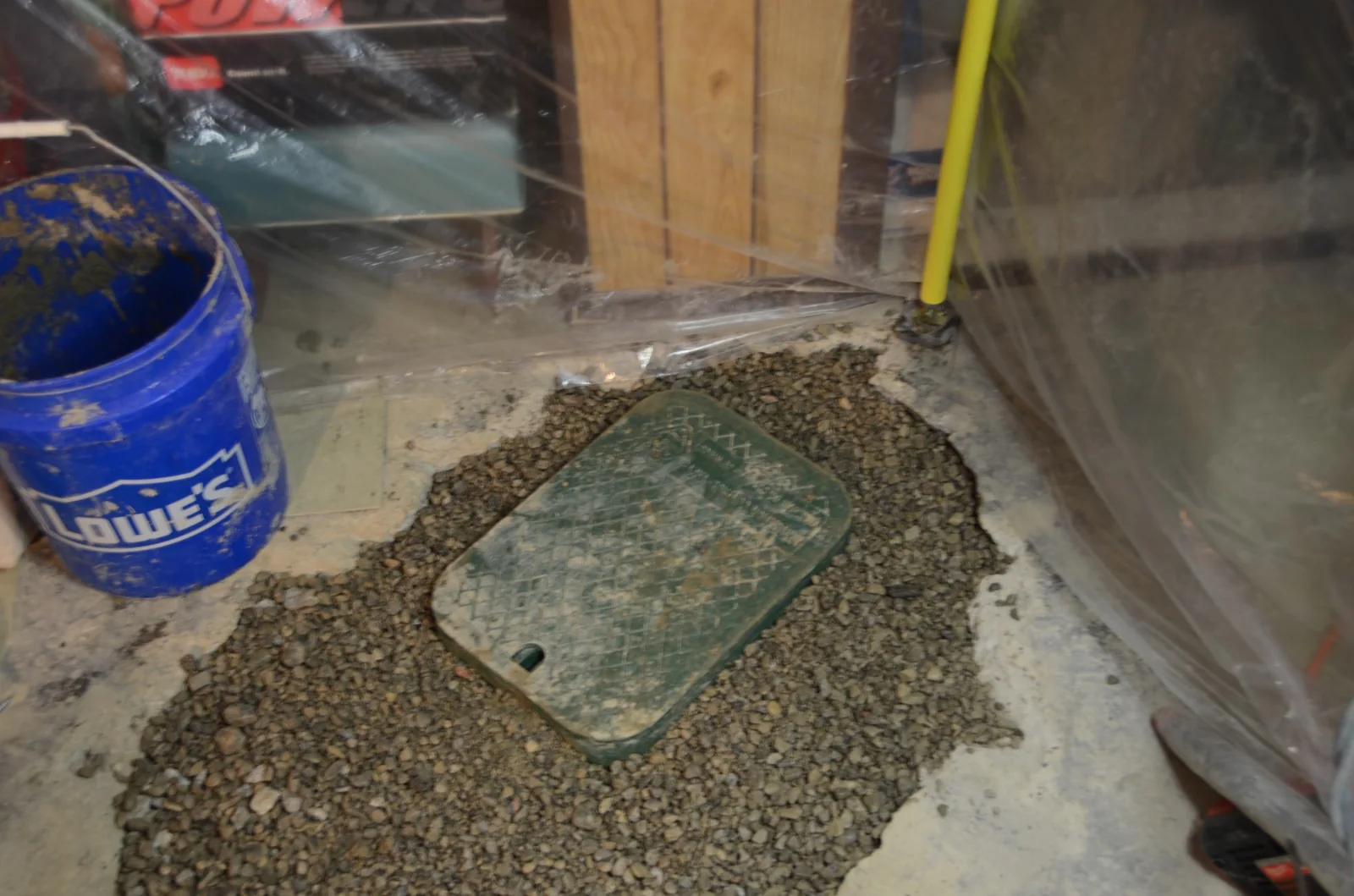 Backwater valve access cover surrounded by granular base before concrete finishing