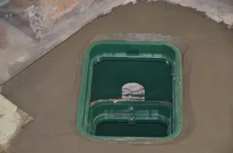 Restored basement floor around a completed backwater valve access cover