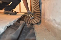 Interior drainage membrane being secured at the basement wall and floor edge